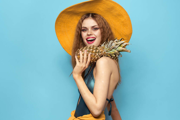 woman in beach hat pineapple holding swimsuit exotic fruits blue background vacation - Photo, Image