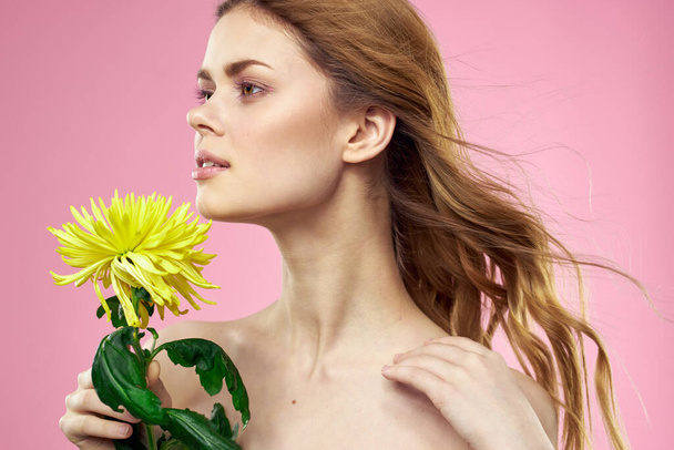 Porträt einer Frau mit gelben Blumen auf rosa Hintergrund Make-up im Gesicht - Foto, Bild