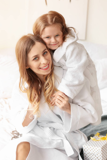 Jonge vrouw met haar dochtertje in slaapkamer - Foto, afbeelding