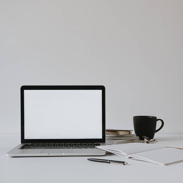 Ноутбук з порожнім копіювальним простором макет екрану на столі з чашкою кави, паперовий лист на білій стіні. Мінімалістичний робочий простір домашнього офісу
. - Фото, зображення