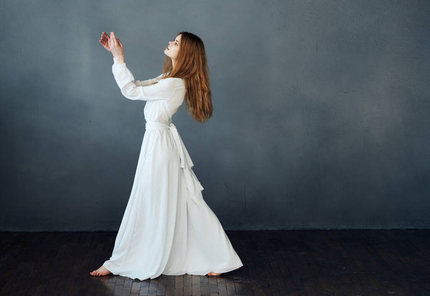 Mulher bonita em um vestido branco para o chão em um fundo cinza em pleno crescimento - Foto, Imagem