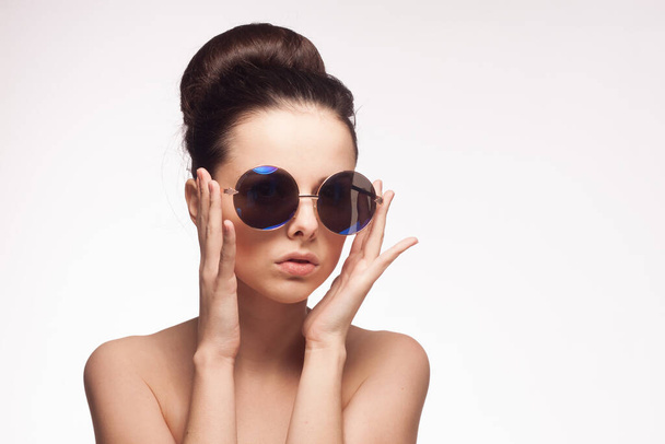woman wearing sunglasses naked shoulders charm fashion light background - Photo, Image