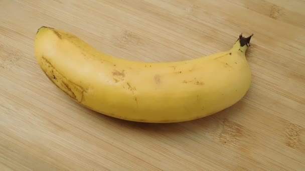 érett magányos banán fekszik egy régi fa asztalon. - Felvétel, videó