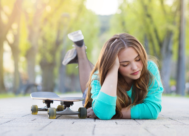 Girl with skateboard lying in alley - Fotoğraf, Görsel