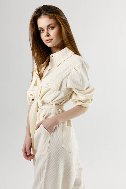 pretty woman in white jumpsuit holds hand in pocket attractive look model - Photo, image