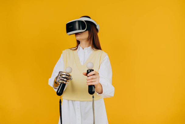 Lady met bionische arm virtual reality bril en joysticks - Foto, afbeelding