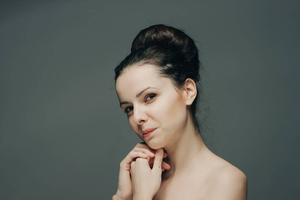 pretty brunette on gray background naked shoulders clean skin cosmetology - Foto, Imagem