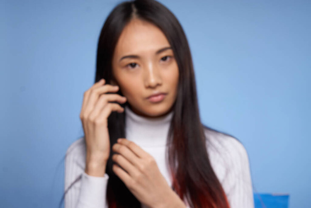 Frau asiatisches Aussehen Porträt auf blauem Hintergrund weißer Pullover Modell - Foto, Bild