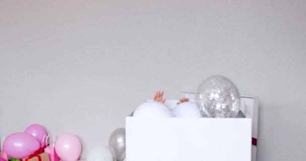 Linda y alegre niña en vestido rosa saltar de la gran caja de regalo regalo con globos en casa fiesta de cumpleaños serpentinas, Feliz cumpleaños. Celebrando - Metraje, vídeo