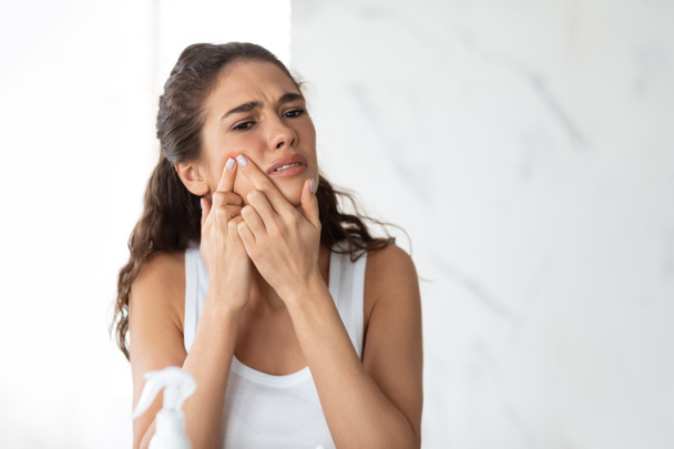 Senhora frustrada com problema de acne espremendo espigão na bochecha interior - Foto, Imagem