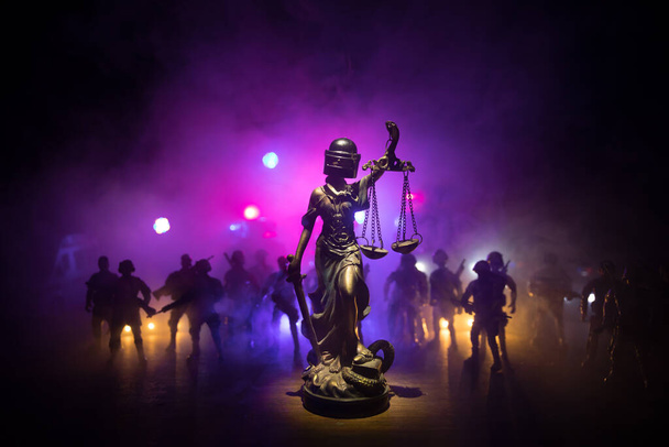 Kein Gesetz oder Diktaturkonzept. Die Statue der Gerechtigkeit mit Schutzhelm der Bereitschaftspolizei. Kreative Kunstwerke Dekoration mit bunten getönten nebligen Hintergrund. Selektiver Fokus - Foto, Bild