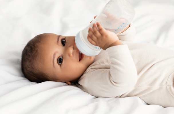Aranyos kis afro-amerikai baba iszik üvegből - Fotó, kép