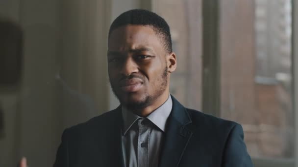 Porträt eines unglücklichen ethnischen Geschäftsmannes afroamerikanischer Arbeiter, der im Büro vor Fensterhintergrund steht, legt seine Handflächen vor ihn und macht eine verbotene Verweigerungsgeste, um seine Abscheu zum Ausdruck zu bringen - Filmmaterial, Video