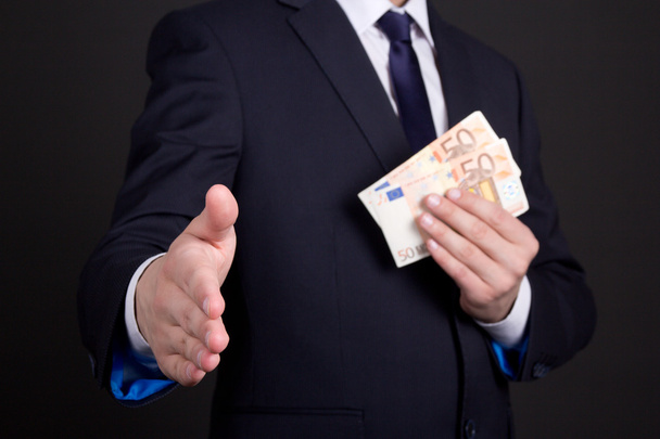 rüşvet kavramı - el sıkışma için hazır para ile takım elbiseli adam - Fotoğraf, Görsel