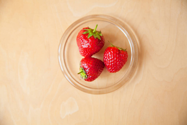 strawberries in a glass bowl on a wooden background - Photo, Image