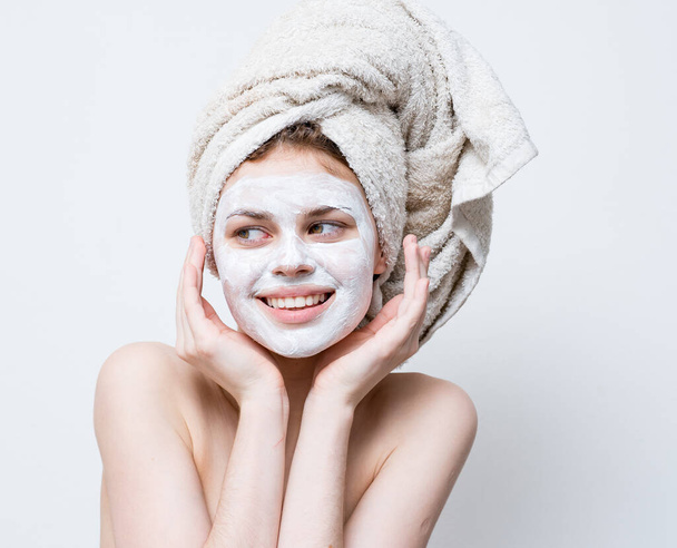 hezká žena s ručníkem na hlavě a bílou maskou proti černým tečkám na tváři - Fotografie, Obrázek