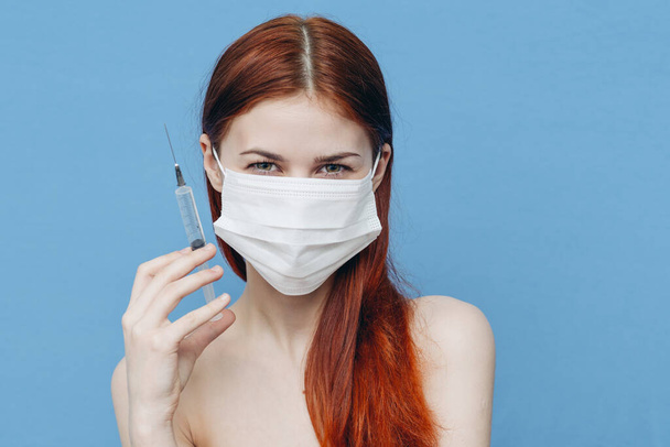 kék hátterű nő orvosi maszkban és fecskendők a kézben botox injekció szépségápolás - Fotó, kép