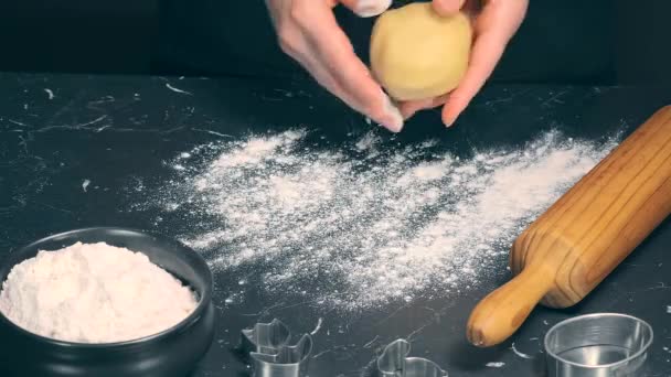 Woman prepares butter cookies at home in the kitchen, the table is sprinkled with flour, rolls out the dough, cuts out the shape, the concept of cooking festive food, christmas or easter sweets - Footage, Video