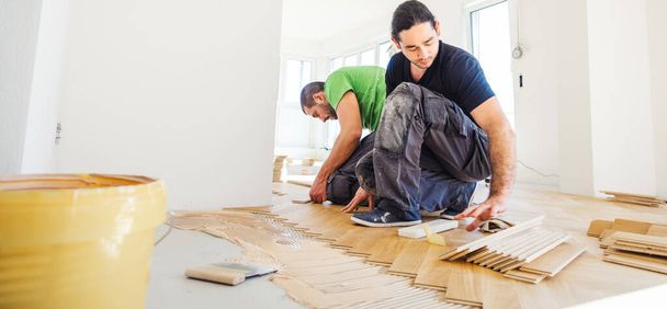 uomini che installano pavimenti in parquet di quercia durante il miglioramento domestico   - Foto, immagini