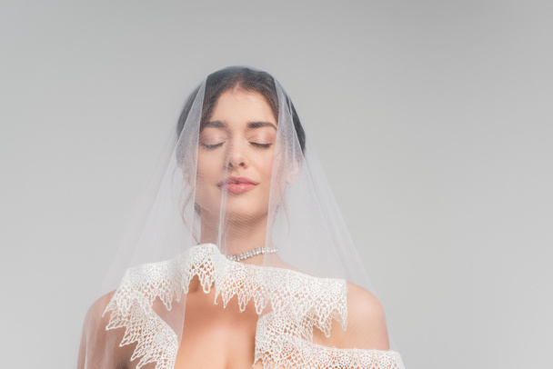 charming woman in veil standing with closed eyes isolated on grey - Photo, Image