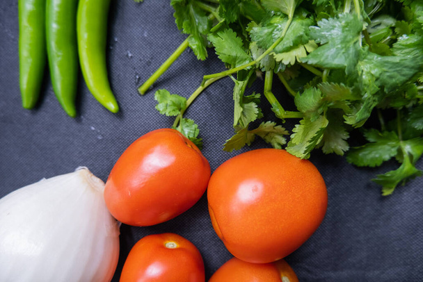 Chili peppers, onion, and a tomato above coriander - Photo, Image