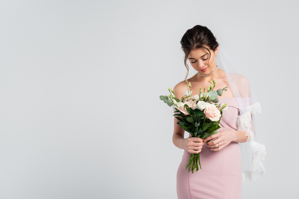 fiatal, érzéki nő elegáns ruha gazdaság esküvői csokor elszigetelt szürke - Fotó, kép