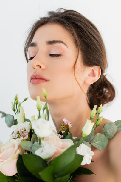 junge Frau mit Brautstrauß posiert mit geschlossenen Augen isoliert auf weiß - Foto, Bild