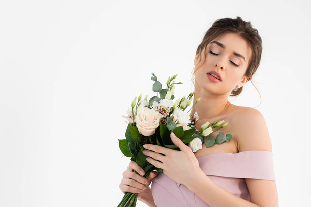 sensual fiancee holding wedding bouquet while posing with closed eyes isolated on white - Photo, Image