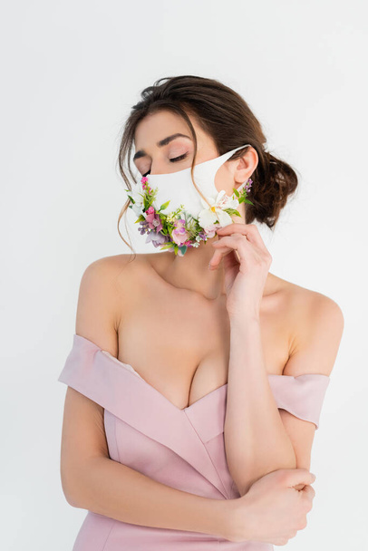 nő rózsaszín ruha és orvosi maszk virágok pózol elszigetelt szürke - Fotó, kép