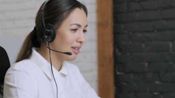 Smiling woman call centre operator, customer support agent wears headset consults client online typing on laptop, talk in internet computer chat, helpline operator secretary make conference video call - 映像、動画