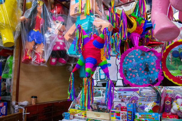 Kleurrijke pinatas met papieren strepen hangend in een markt - Foto, afbeelding