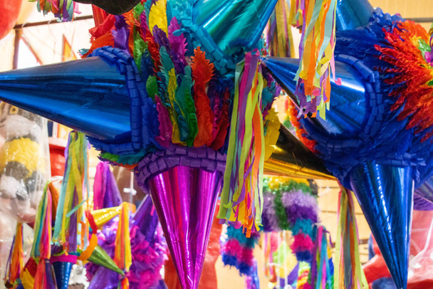 Pinatas coloridas con rayas de papel colgando dentro de un mercado - Foto, Imagen