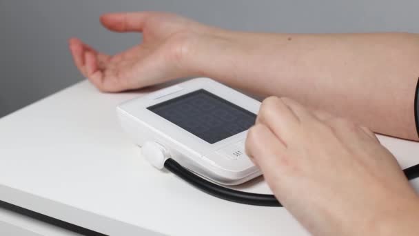 An adult or an elderly woman measures blood pressure pressure with portable digital tonometer - Footage, Video