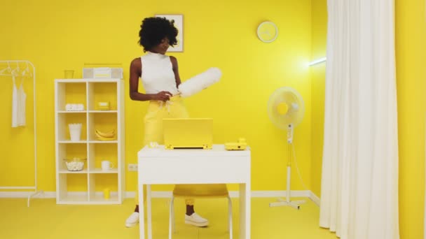 Schwarze stilvolle Dame putzt gelbes Zimmer - Filmmaterial, Video