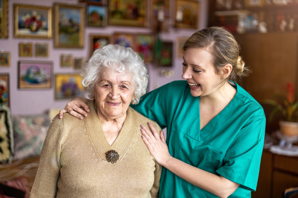 Friendly nurse supporting an elderly lady - Foto, Imagen
