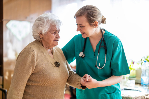 Friendly nurse supporting an elderly lady - Foto, afbeelding