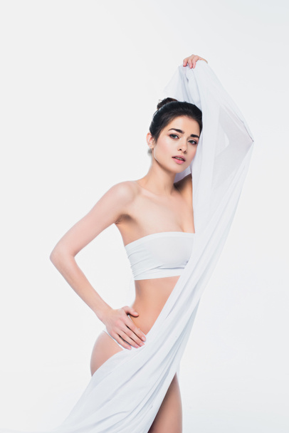 Hübsche Frau in weißer Unterwäsche hält Textil isoliert auf weißer Unterwäsche  - Foto, Bild