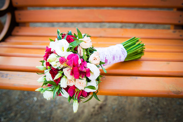 Wedding decoration of a beautiful delicate bouquet lying down on a swing in the park. - Photo, Image