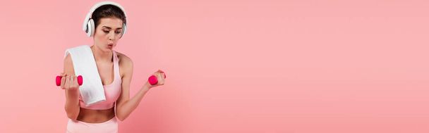 Woman in headphones training with dumbbells isolated on pink, banner  - Photo, Image