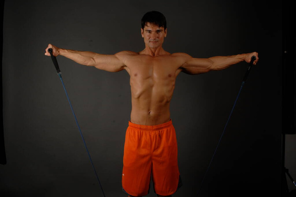 Der sexy Mann trainiert seine Muskeln. - Foto, Bild