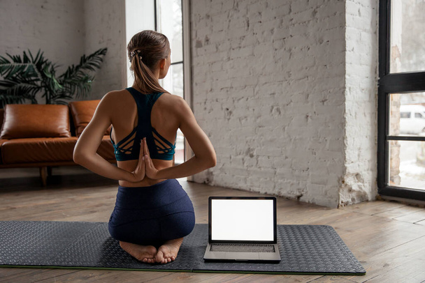 Schöne fitte Yogalehrerin führt virtuellen Yoga-Kurs zu Hause auf einer Videokonferenz durch.  - Foto, Bild