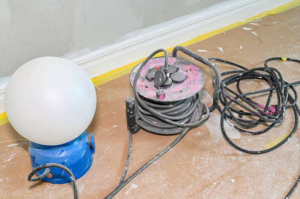 lámpara de trabajo y cable de extensión en papel de piso - Foto, imagen