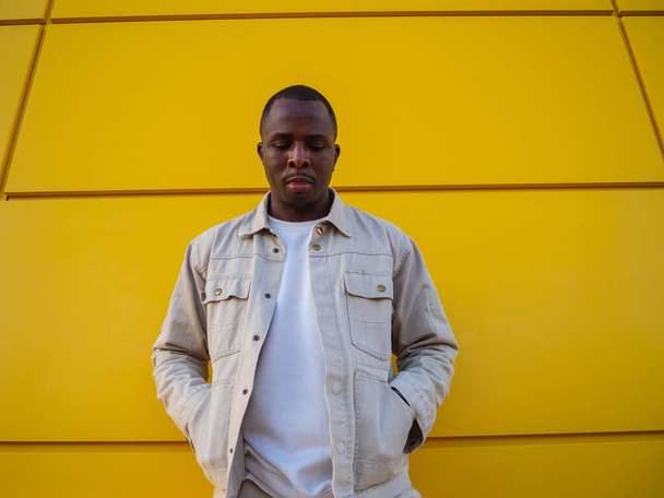 A fashionable black Spanish male posing against a yellow wall - Foto, imagen
