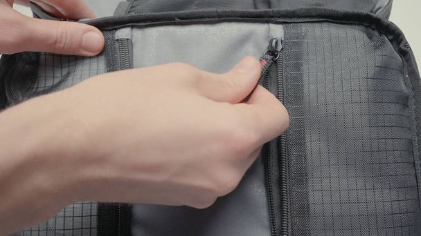 Hand closes gray bag. Action. Close-up of hand closes lock of small gray bag. Simple grey bag for small items - Zdjęcie, obraz