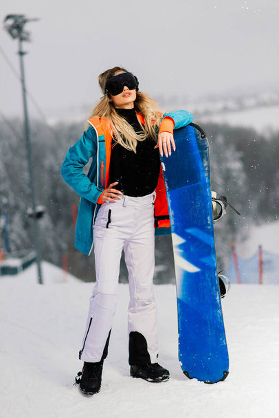 Young sporty smiling woman in winter with snowboard, glasses - Photo, Image