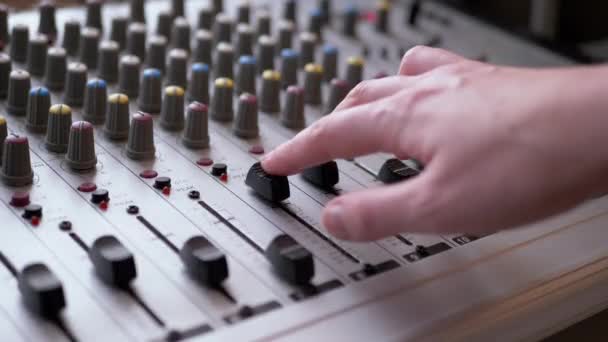 サウンドエンジニア、 DJはレコーディングスタジオでオーディオミキサー上の指でスライダーを移動します - 映像、動画