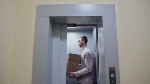Jong stel uit de lift met kartonnen dozen, verhuizen naar een nieuw appartement - Video