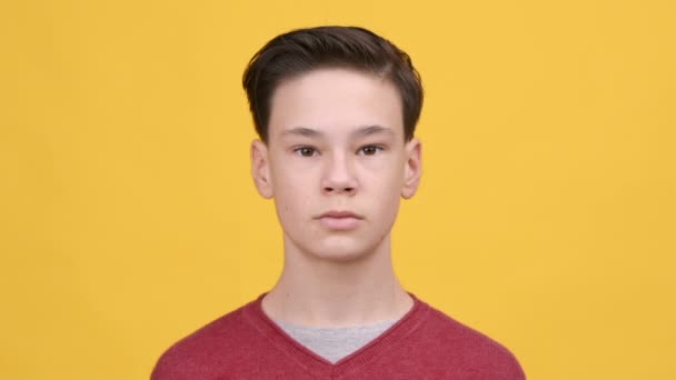 Portret van ernstige tiener jongen poseren over gele achtergrond - Video