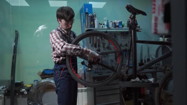 Sklep rowerowy mechanik mocowania koła rowerowego w warsztacie. Naprawa serwisantów, cykl konserwacji. Velocipede naprawy rowerów w sklepie rowerowym. Koncepcja usługi naprawy rowerów. Pojazdy przyjazne dla środowiska - Materiał filmowy, wideo