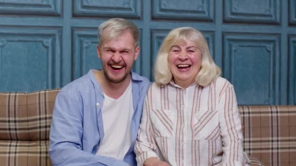 Mère aînée heureuse et jeune adulte souriant étreignant son fils en riant en regardant la caméra - Séquence, vidéo